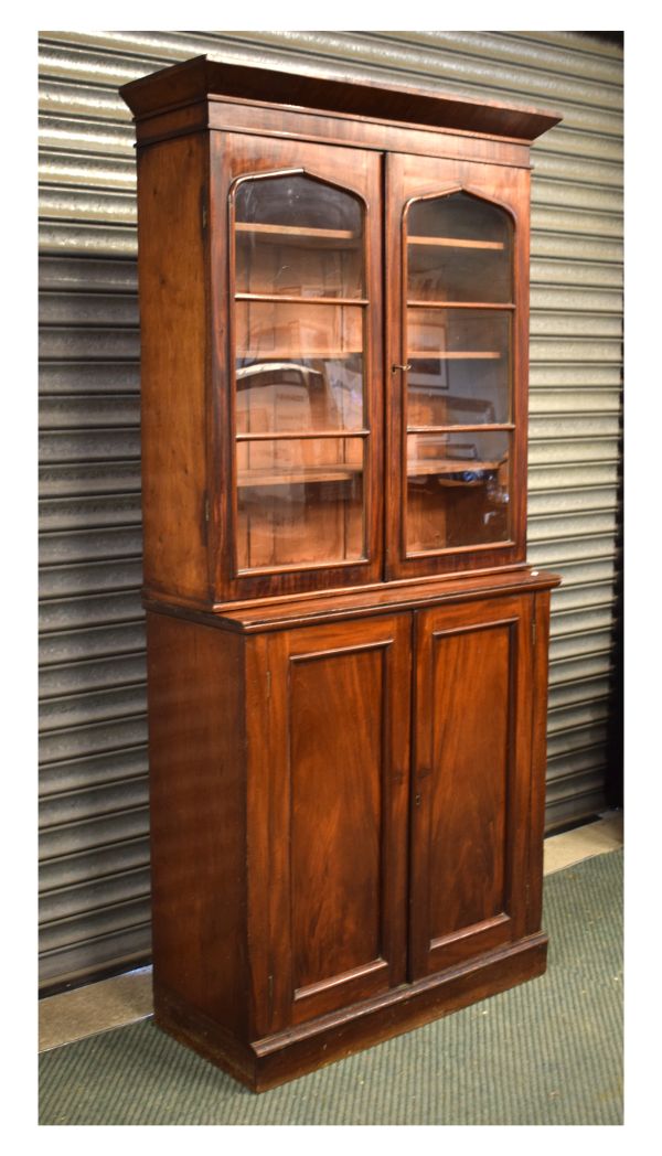 19th Century mahogany bookcase on cabinet, the upper section with arch-glazed twin doors enclosing