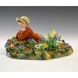 Crown Staffordshire figure depicting a young boy amongst floral encrusted ornamentation, 23cm x 19xm