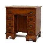 Reproduction yew wood finish kneehole desk having an inset leather writing surface and fitted
