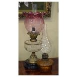 Cranberry glass paraffin lampshade, together with a brass and clear glass paraffin lamp on