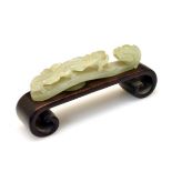 19th Century Chinese carved jade belt hook of traditional figural form, 10cm long on a hardwood