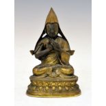 South East Asian gilt bronze figure of a hooded Buddha, seated on a lotiform base, his hands in