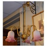 Brass and mottled pink glass three branch ceiling light with tubular stem and scroll arms over three