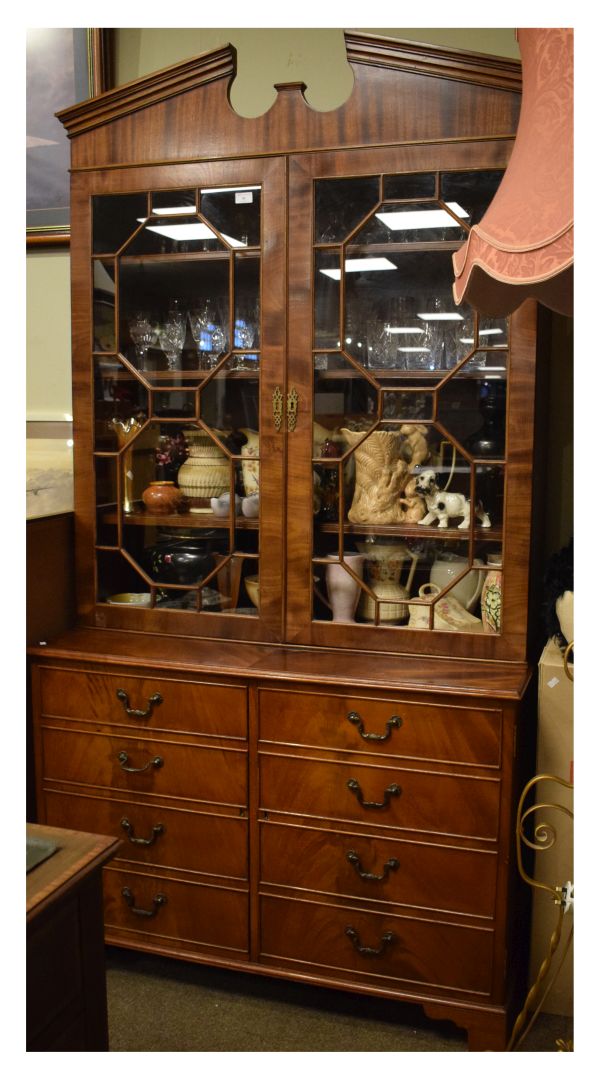 Reproduction mahogany-finish bookcase on cabinet on the Georgian taste, the 'broken' pediment over