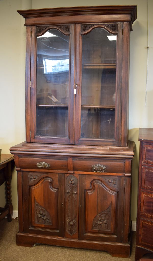 Early 20th Century walnut bookcase on cabinet, the upper stage having a pair of arch-glazed doors