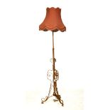 Early 20th Century gilt metal adjustable standard lamp of open scroll design on tripod support, with