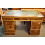 Reproduction yew-wood twin pedestal office desk having a gilt-tooled green skiver over three