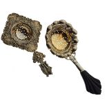 Two Continental white metal tea strainers, the first with ebonised handle, stamped .830, the