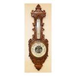 Early 20th Century carved oak cased aneroid barometer and thermometer, the white ceramic dial with a