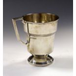 George VI silver christening mug having an angled handle and standing on a circular foot,