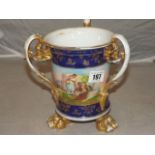 A CONTINENTAL THREE HANDLED & FOOTED POT ,DECORATIVE PANELS WITH GILT ON A BLUE GROUND