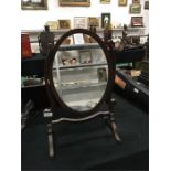 An Edwardian oval dressing table mirror in mahogany frame.