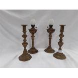 Two brass candle sticks and two brass lamps .
