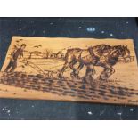 A wooden poker work panel of ploughing horse along with two scenic prints.