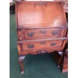 A two drawer mahogany bureau resting on cabriole legs.