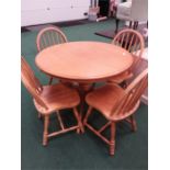A beechwood circular dining table with four stickback chairs.