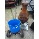 A cast iron chiminea together with a winter salt spreader and a small dog cage.