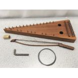 A wooden zither with bow and accessories.