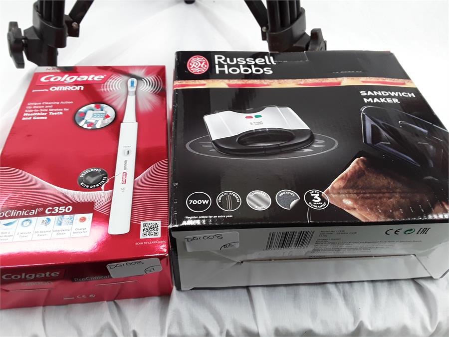 A camera tripod together with a boxed Colgate Omron electric toothbrush and a boxed Russell Hobbs