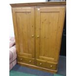 A large double pine wardrobe with two drawers under.