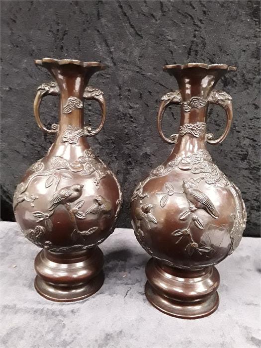 Two Chinese bronzed brown coloured metal vases decorated in high relief depicting birds.
