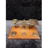 A miniature set of postal scales on wooden base with weights.