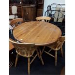 A modern round pine dining table with four matching chairs.