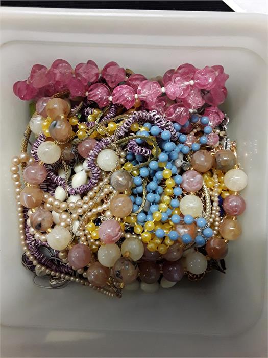 A plastic tub of jewellery. beads etc