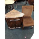 A small oak corner cupboard together with a brown upholstered chair.