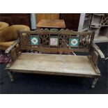 A three seater colonial design oak garden bench with flip top and tile decoration.