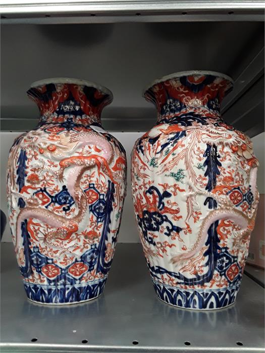 A pair of large Japanese Imari vases decorated with dragons in blue and red.