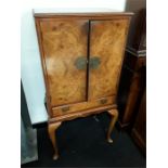 A reproduction walnut cocktail cabinet on cabriole legs.