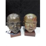 A pair of bronzed Childs heads stamp to the side reads Cire perdu by the Meridian cc Melbourne