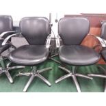 A pair of chrome and black hairdresser's rise and fall chairs.