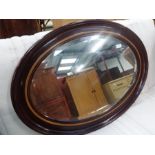 A bevelled edge oval hall mirror in a mahogany frame.