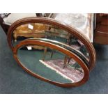 Two oval shaped wood framed wall mirrors.