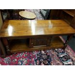 An old charm style coffee table with magazine shelf and central cupboard.