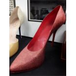 A very large red glitter shop display high heeled shoe.