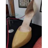 A very large yellow/cream shop display high heeled shoe (af).