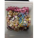 A plastic tub of jewellery. beads etc