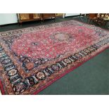 A Persian design large wool carpet on a pink/purple ground, all over floral border, central and