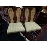 A pair of Queen Anne design walnut side chairs with caned backs resting on carved legs
