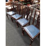 A set of four dark wood dining chairs with blue leather seat pads.