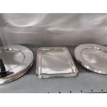 A collection of silver plated dinner plates and a serving tray.