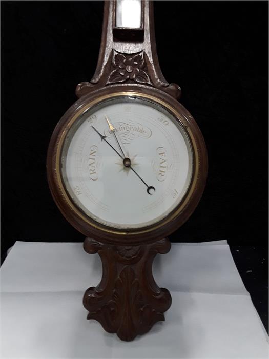 A banjo barometer in a carved oak case.