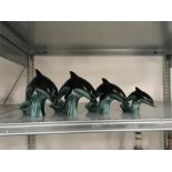 Four green Poole Pottery dolphins.