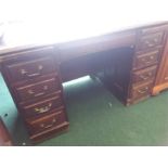 An oak twin pedestal desk with inset green leather top.