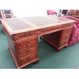 A yew wood twin pedestal desk with inset green leather top.