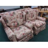 A three piece suite comprising a three seater and two armchairs in floral pattern material.