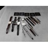 Collection of watches and pens including commemorative coins.